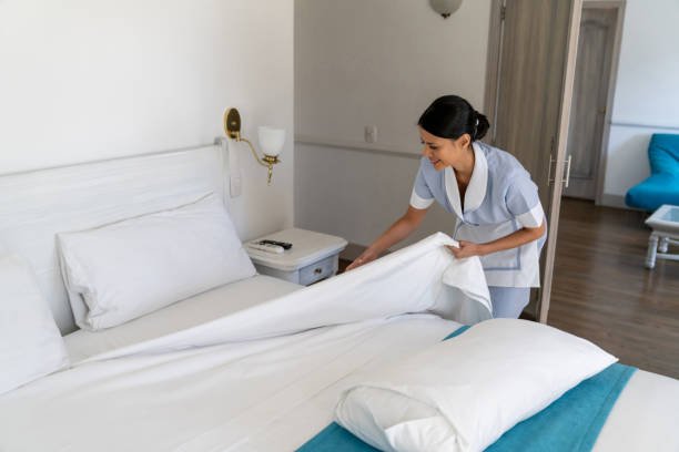 Housekeeping staff cleaning the bed