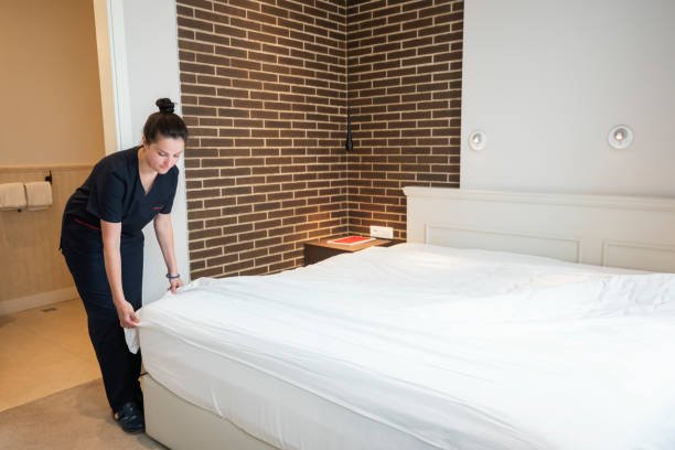 Maid making the bed at hotel room