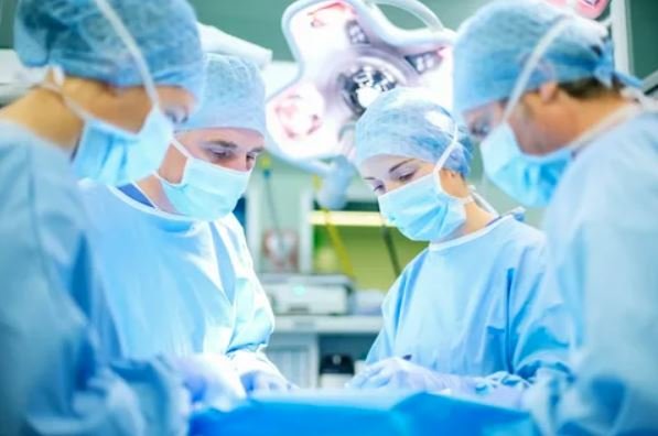 A team of surgeons collaborates in a sterile operating room, focused on a surgical procedure.