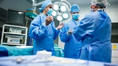 Three surgeons in blue scrubs engaged in conversation, collaborating on a medical procedure or patient care.