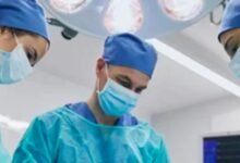 Three surgeons wearing blue scrubs and surgical masks, focused and ready for a surgical procedure in a sterile environment.