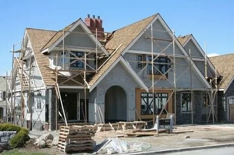 A house under construction, featuring scaffolding and wooden beams, showcasing the building process.