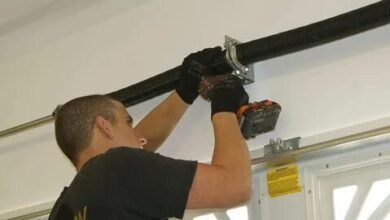 A man repairs a garage door using a tool, demonstrating hands-on maintenance and home improvement skills.